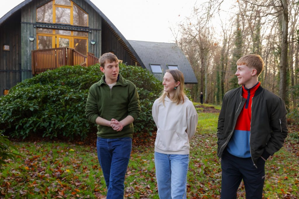 Three Coillte scholars walking on grass and talking outside in front of trees