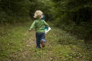 Child running through forest path