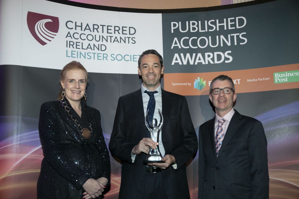 Picture of Coillte's chief financial officer holding a trophy for published accounts awards with two of the judges