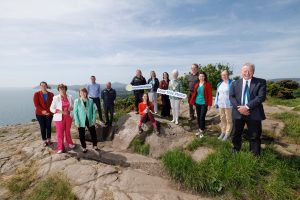 Group of people standing on a hilltop overlooking the sea to announce the launch of the love this place campaign 2023
