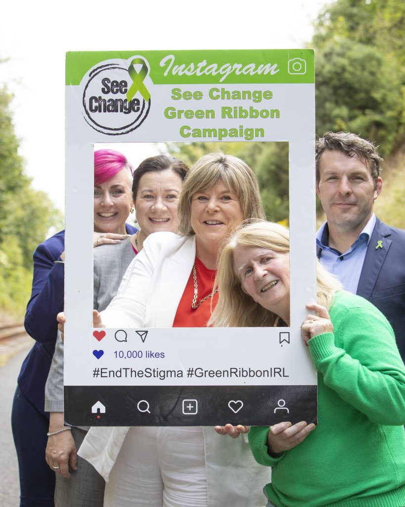 Barbara Brennan (SeeChange), Imelda Hurley (CEO Coillte), Minster for Older People and Mental Health Mary Butler, Finola Colgan (Mental Health Ireland) and Brian Rushe (IFA Deputy President) at the launch of the SeeChange Green Ribbon Campaign peeking through a picture frame with Green Ribbon details on it