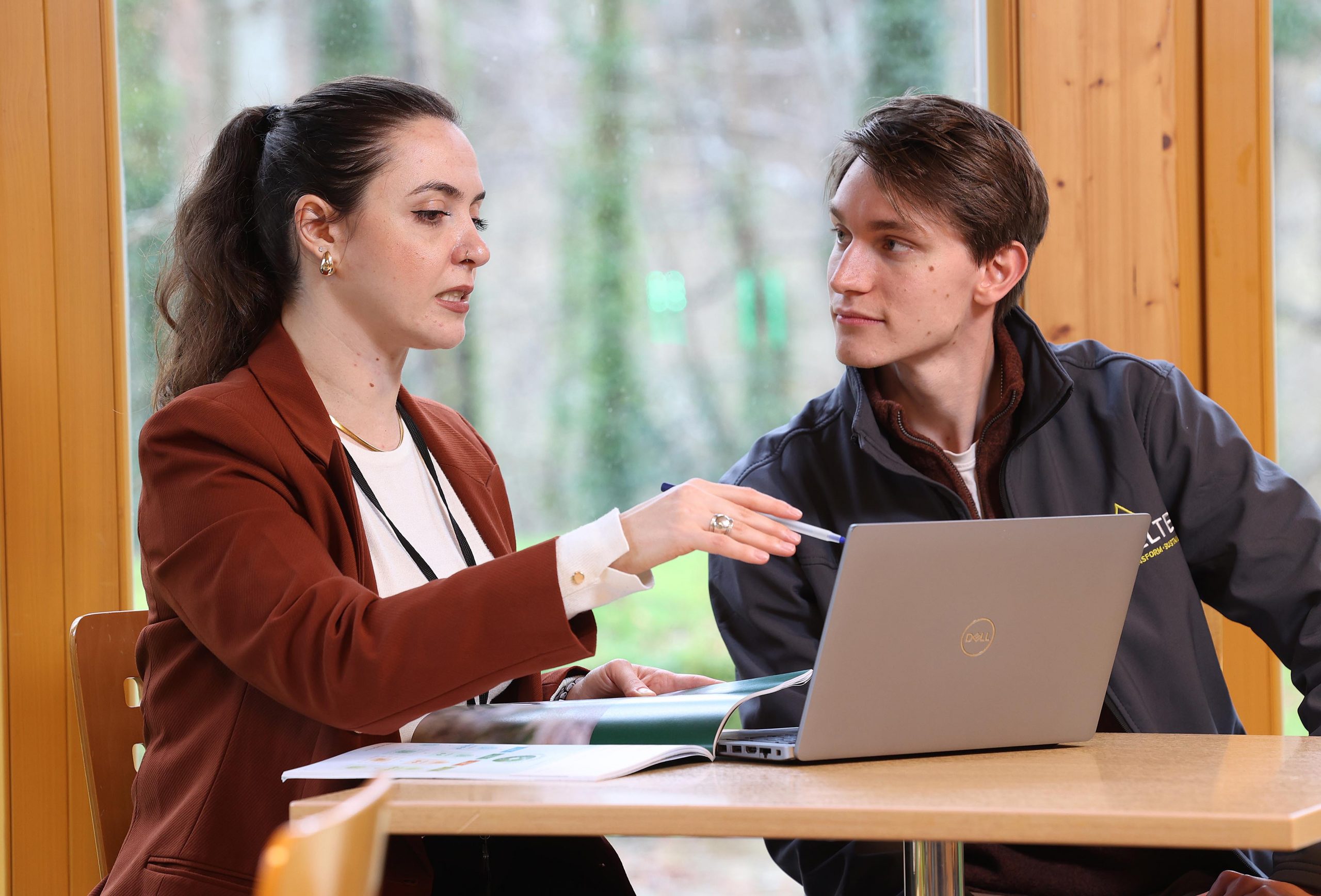 Two foresters sitting in an office working at a desk over a laptop