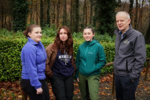 Three students, winners of the Coillte 2024 Forestry Scholarship standing next to Coillte's Managing Director in front of a forest