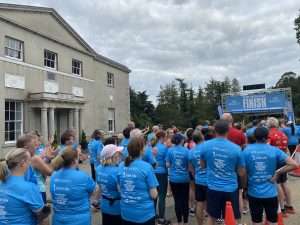 Runners wearing blue tee shirts standing at a race finish line in front of avondale house county wicklow