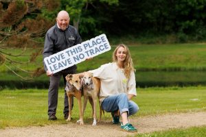 Pat Neville, Coillte holding a love this place, leave no trace sign next to Thalia Heffernan and her two dogs, Leonard and Charlie