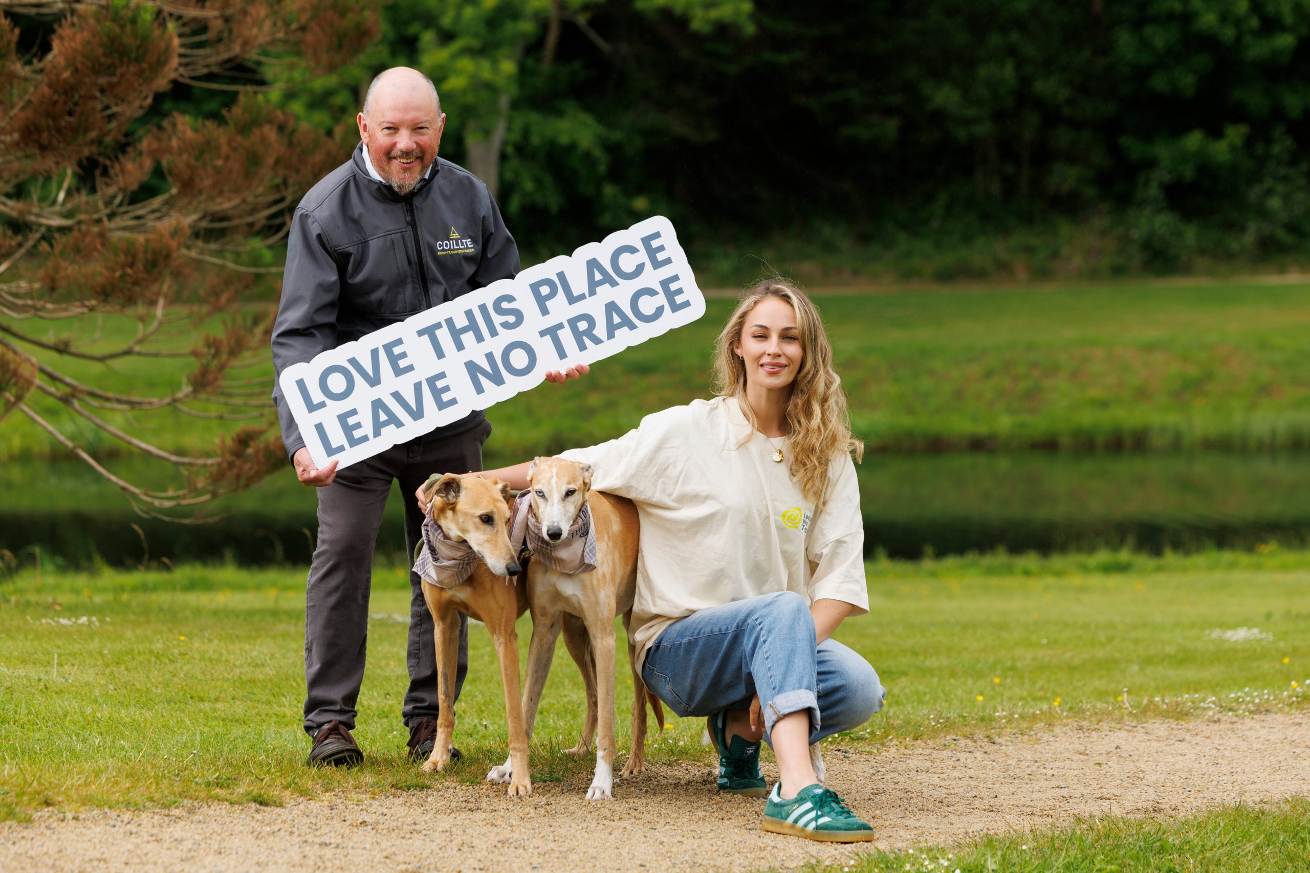 Pat Neville, Coillte holding a love this place, leave no trace sign next to Thalia Heffernan and her two dogs, Leonard and Charlie
